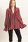 woman wearing a maroon ruffled blouse with a tie at the neckline and long sleeves, paired with black leggings
