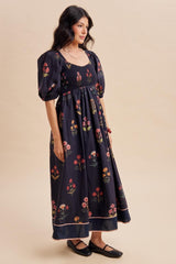 woman wearing a black floral maxi dress with puff sleeves and a smocked bodice