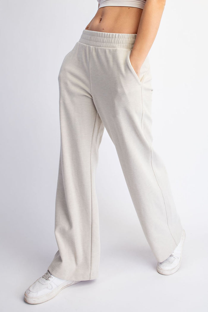 woman wearing light beige wide-leg lounge pants with pockets and an elastic waistband