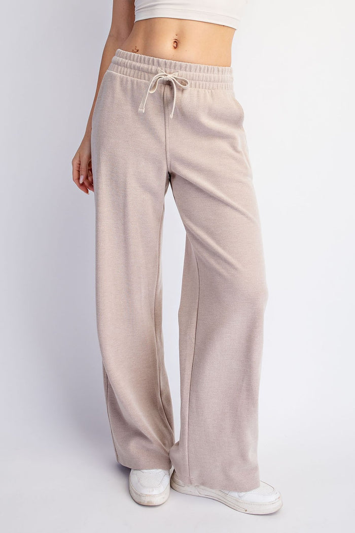 woman wearing beige wide-leg lounge pants with an elastic waistband and drawstring detail