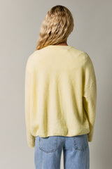 woman wearing a soft yellow oversized sweater seen from the back, paired with light blue jeans