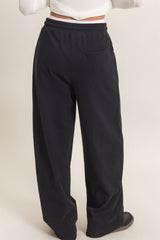 woman wearing black wide-leg sweatpants with a pocket, viewed from the back