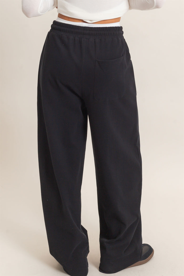 woman wearing black wide-leg sweatpants with a pocket, viewed from the back