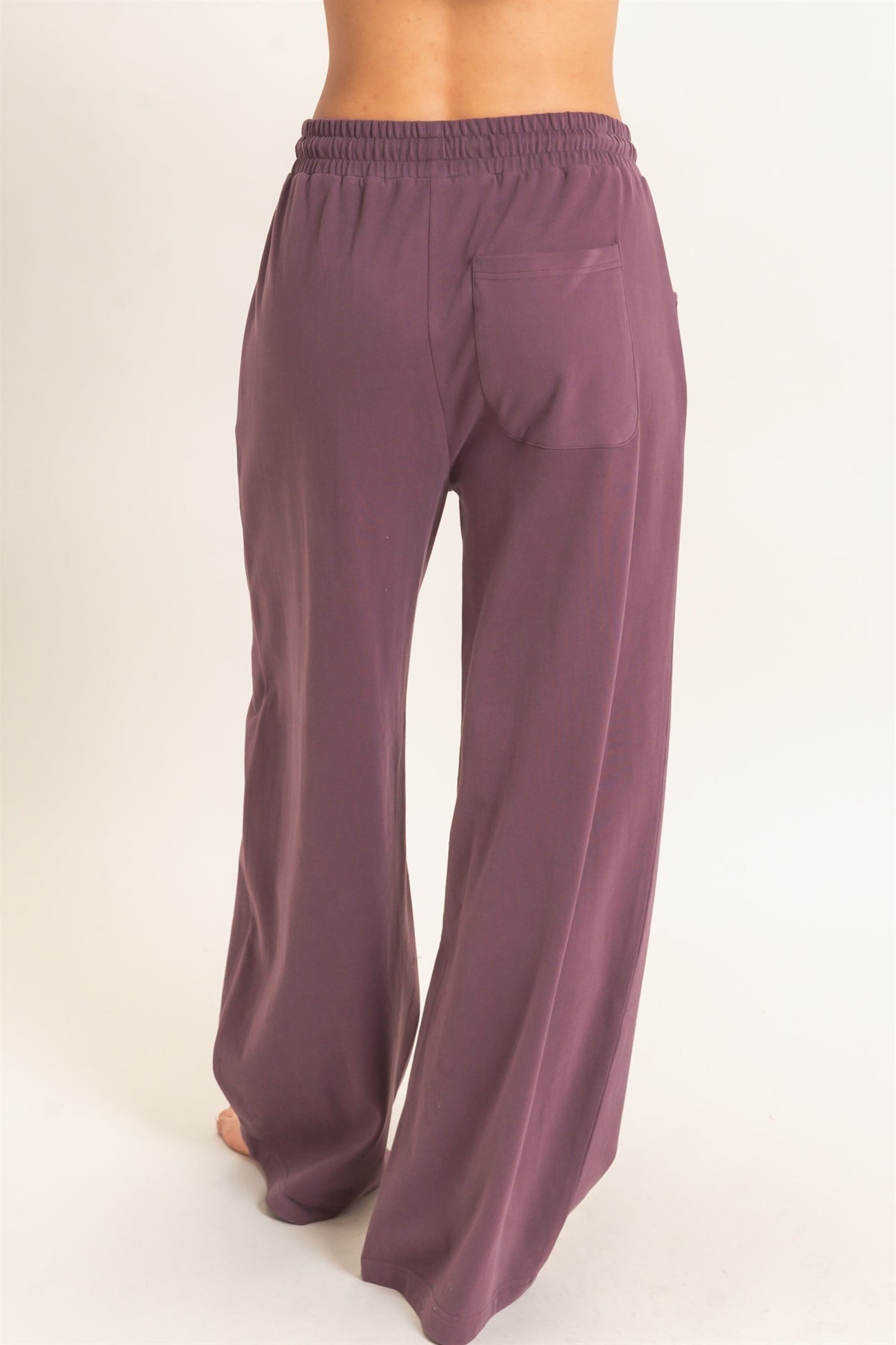 woman wearing a pair of high-waisted, wide-leg pants in a dusty purple color with a back pocket