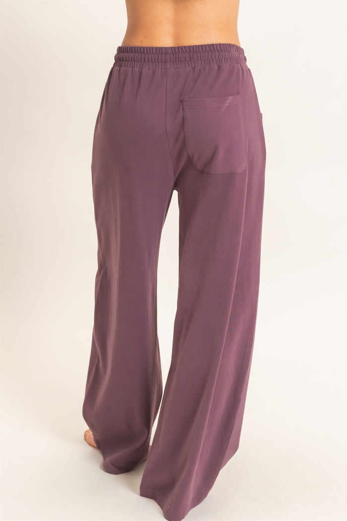 woman wearing a pair of high-waisted, wide-leg pants in a dusty purple color with a back pocket