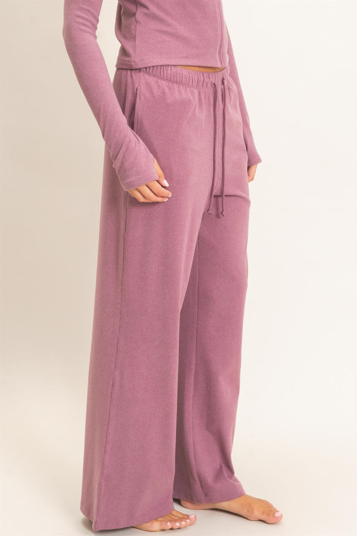 woman wearing loose-fitting mauve lounge pants with an elastic waistband and side pockets