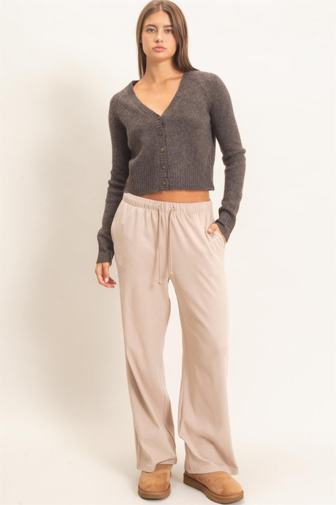 woman wearing a dark gray cropped cardigan and tan wide-leg sweatpants with brown boots