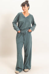 woman wearing a teal loungewear set with a v-neck long sleeve top and drawstring wide-leg pants