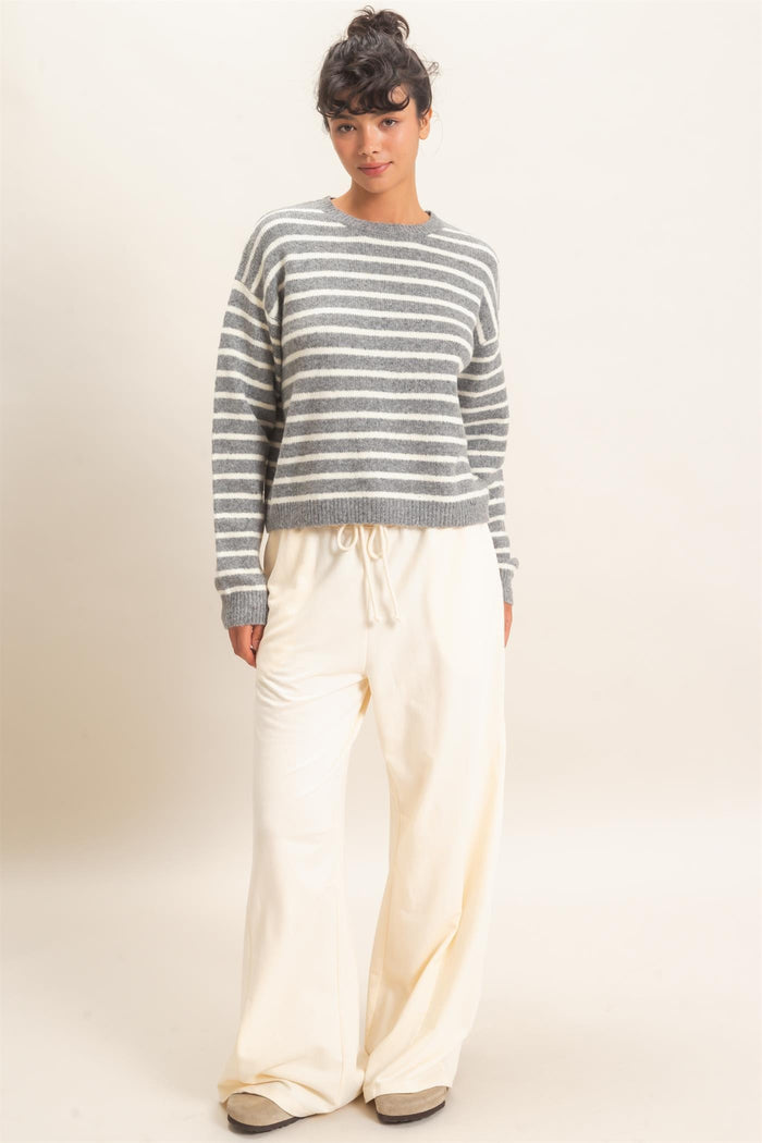 woman wearing a gray and white striped cropped sweater and cream wide-leg pants