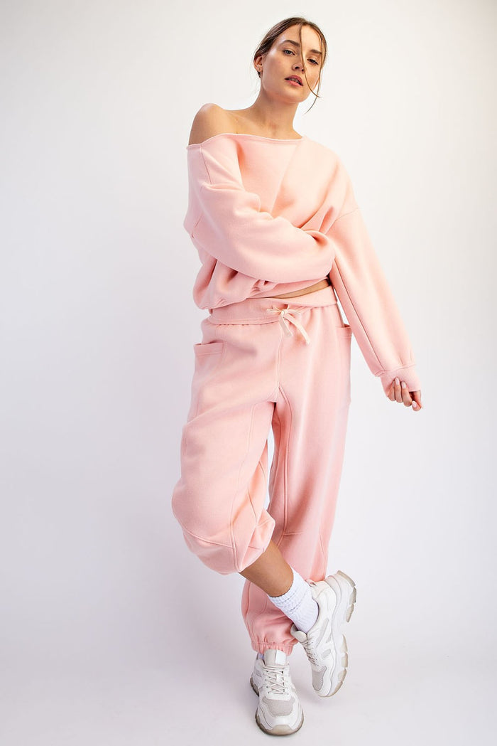 woman wearing a light pink oversized sweatshirt and matching joggers, styled casually with white sneakers