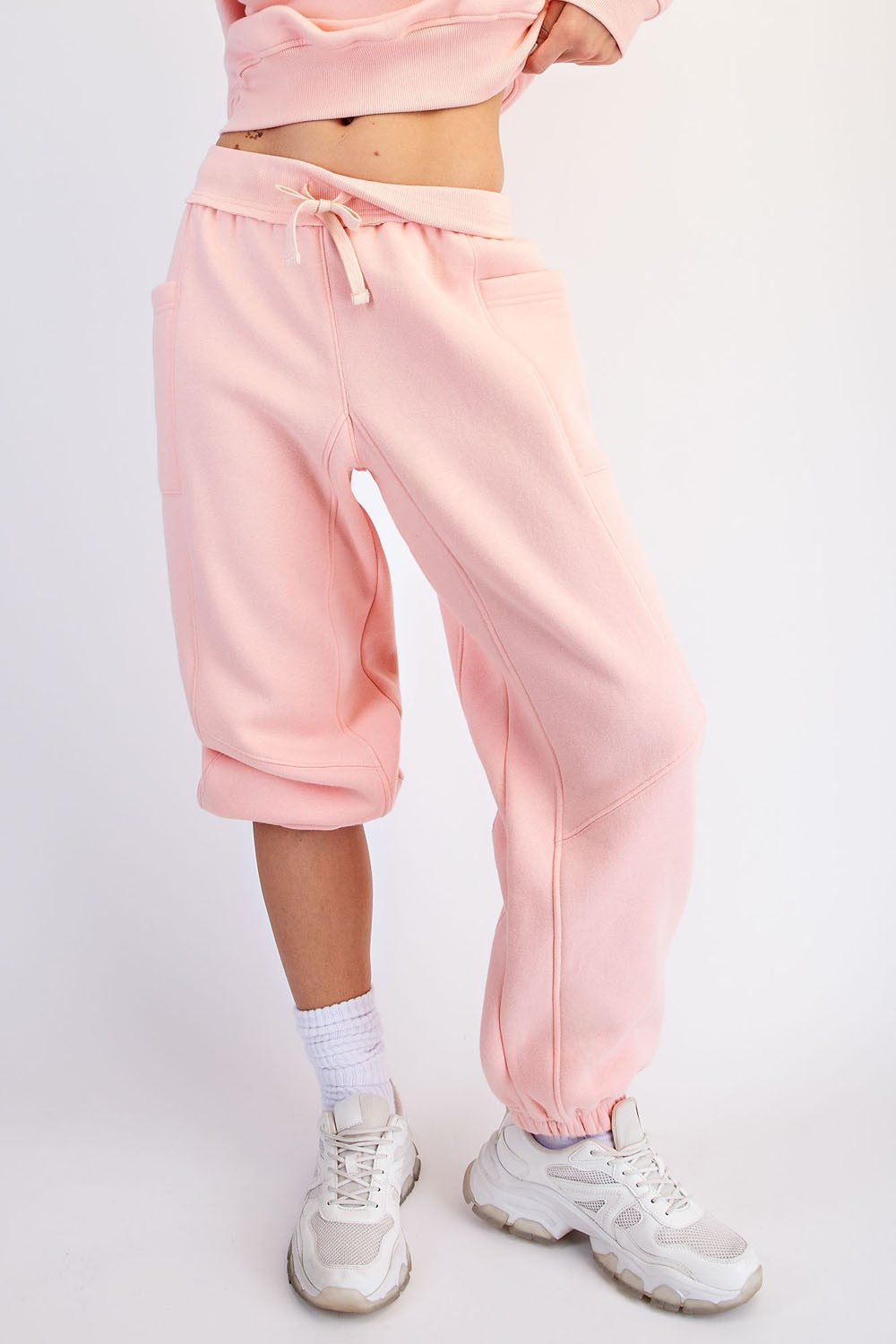 woman wearing pink cropped sweatpants with pockets and an elastic waistband, paired with white sneakers