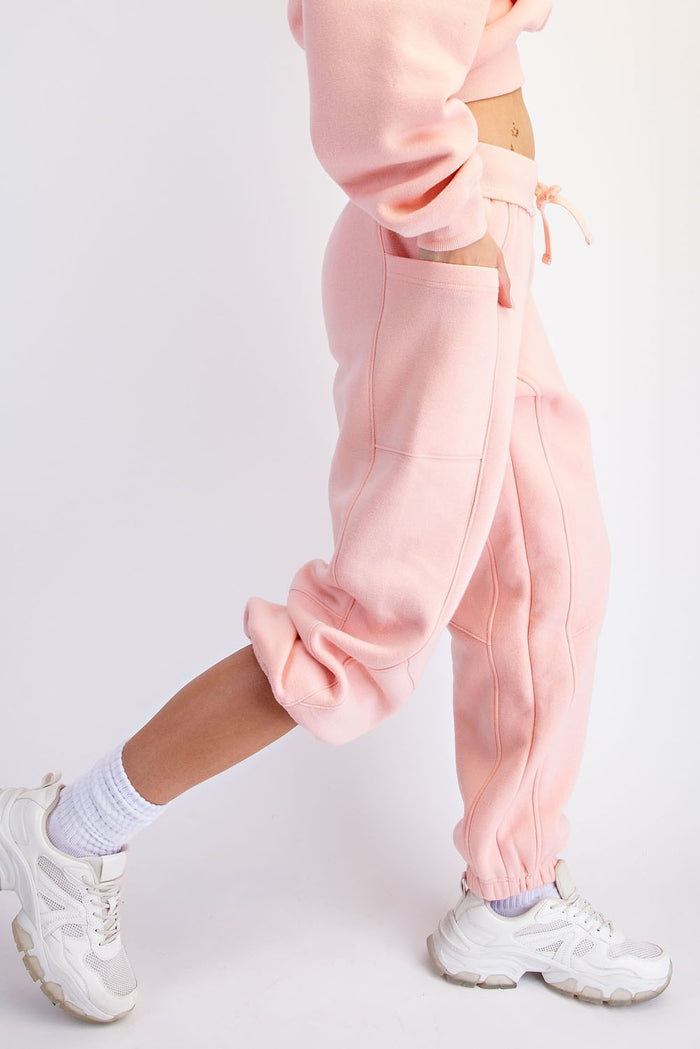 woman wearing light pink jogger pants with pocket details and paired with white sneakers