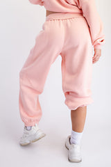 woman wearing light pink cropped sweatpants with elastic cuffs, styled with a matching top and white sneakers