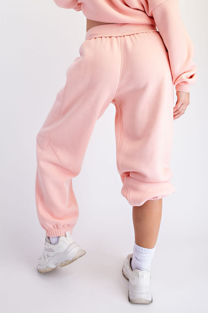 woman wearing light pink cropped sweatpants with elastic cuffs, styled with a matching top and white sneakers