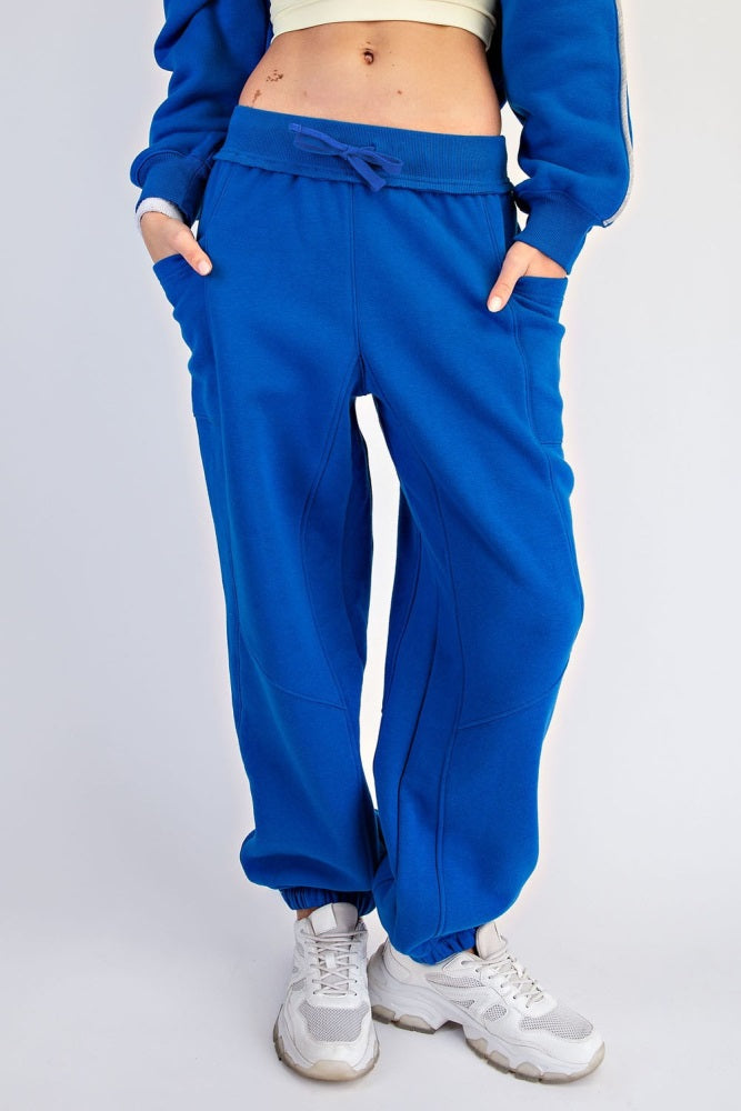woman wearing bright blue jogger pants with pockets and elastic cuffs, styled with a cropped top and white sneakers