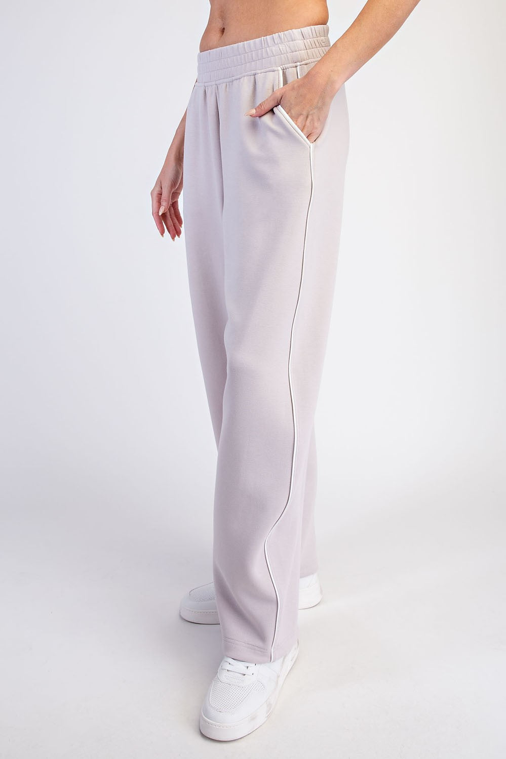 woman wearing light gray high-waisted sweatpants with side pockets and white sneakers