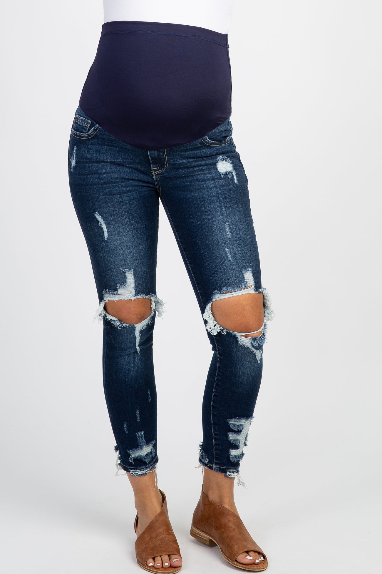 woman wearing a floral maternity tunic top with distressed jeans and a wide-brim hat, holding her baby bump