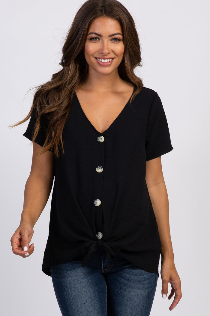 woman wearing a black short sleeve button down top with a front tie knot and blue jeans