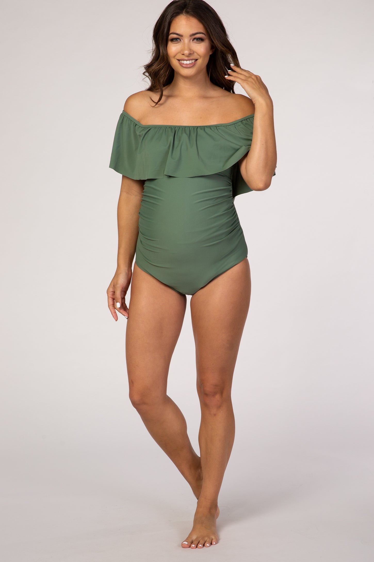 woman wearing a green off-the-shoulder maternity swimsuit with ruffle detailing and a fitted bodice