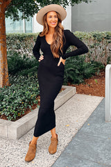 Woman in a black ribbed midi dress, tan wide-brimmed hat, and brown ankle boots posing outdoors