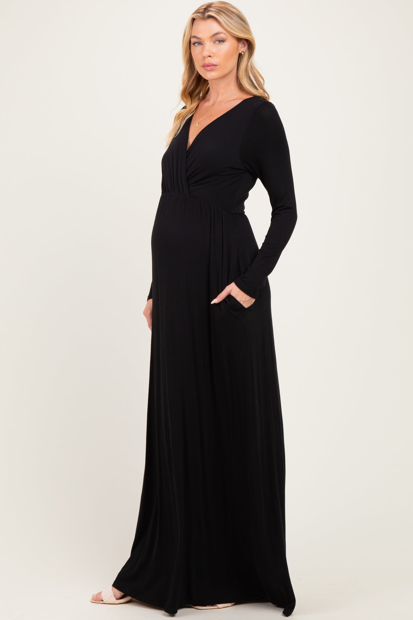 woman wearing a black long sleeve maternity maxi dress with a V-neck and pockets, showcasing her baby bump