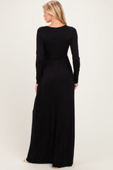 woman wearing a black long sleeve maternity maxi dress, illustrating a flowy fit and empire waist design