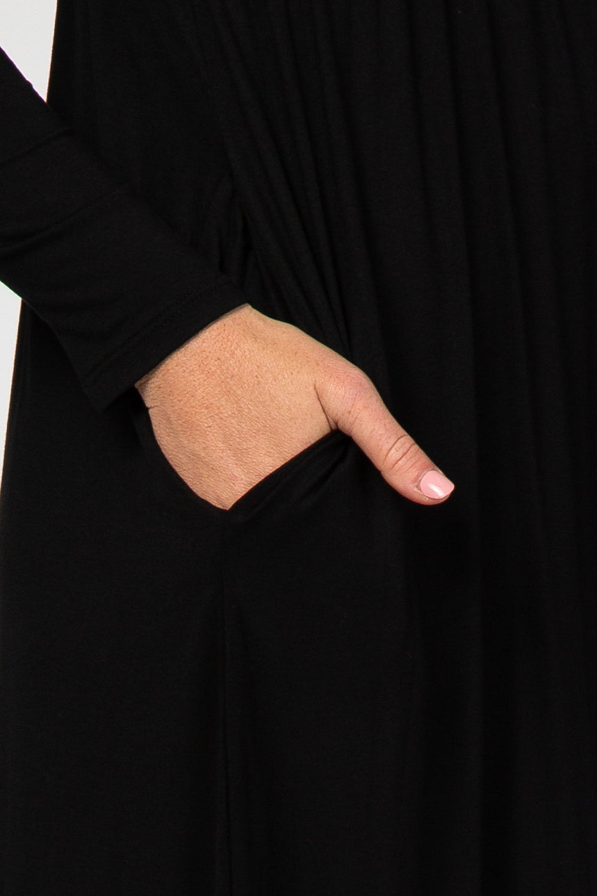 close-up of a woman’s hand in the pocket of a black long sleeve dress