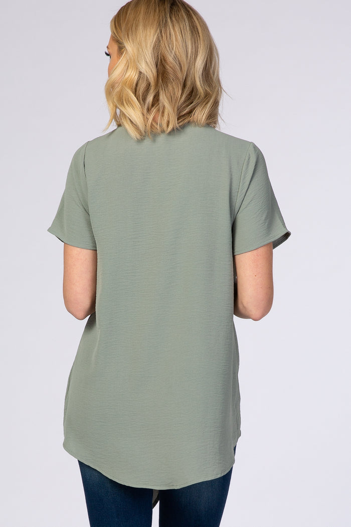 woman wearing a light green short sleeve top, seen from the back, styled with a longer hem and relaxed fit