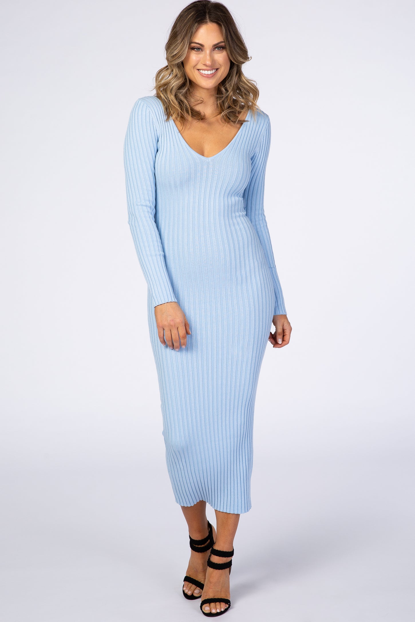 woman wearing a light blue ribbed long sleeve bodycon dress with a deep v-neckline and strappy heels
