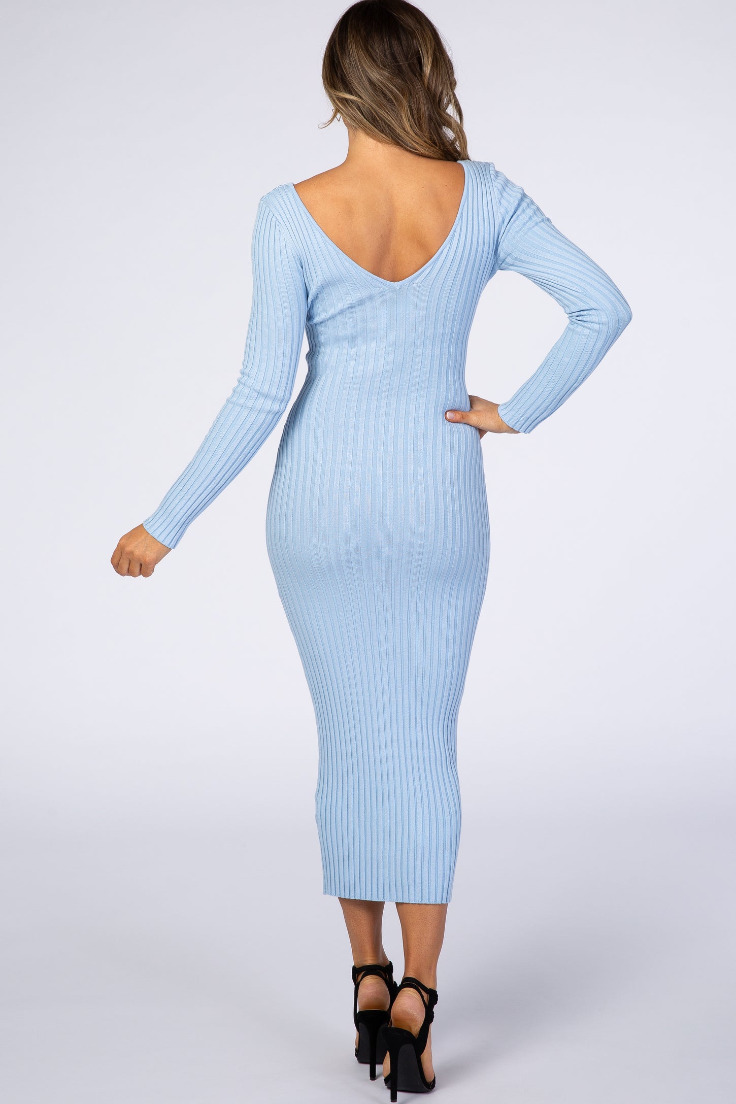 woman wearing a light blue ribbed midi dress with a deep v-back and long sleeves, showing a fitted silhouette