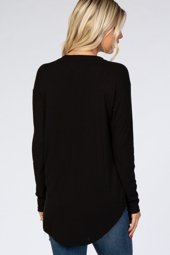 woman wearing a black long sleeve top with a relaxed fit and curved hem, seen from the back