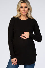 woman wearing a black long sleeve maternity top and holding her baby bump
