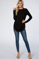 woman wearing a black long sleeve top and blue skinny jeans, styled with beige heels