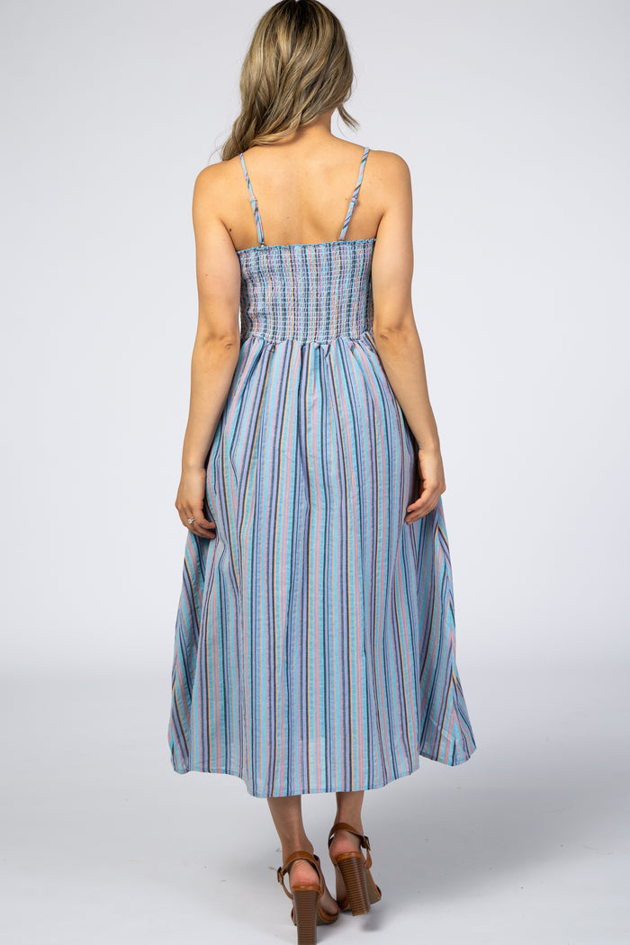 woman wearing a back view of a light blue striped maxi dress with spaghetti straps and a smocked bodice