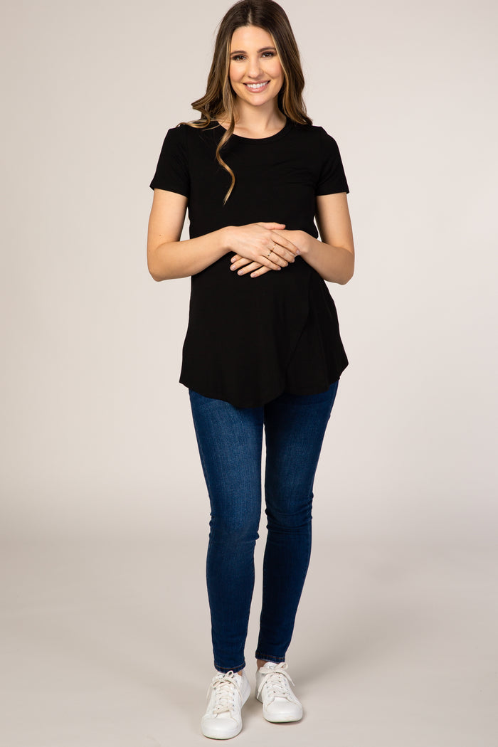 woman wearing a black short sleeve maternity top and showcasing her baby bump with blue skinny jeans