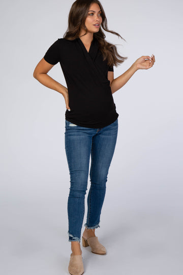 pregnant woman wearing a black short sleeve wrap maternity top and blue skinny jeans