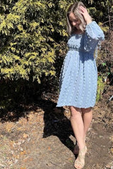 woman wearing a light blue puff sleeve dress with textured details and a relaxed fit, standing outdoors