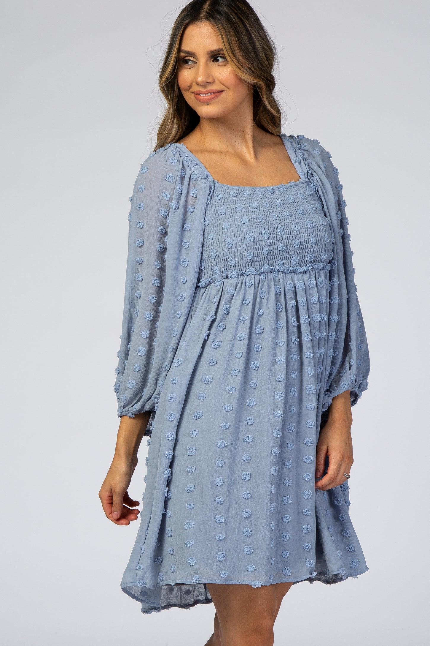 woman wearing a light blue puff sleeve dress with a smocked bodice and textured dot details