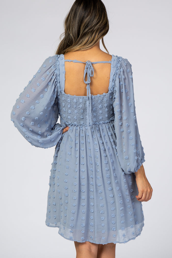 woman wearing a light blue short dress with puff sleeves and a smocked back, featuring textured floral details