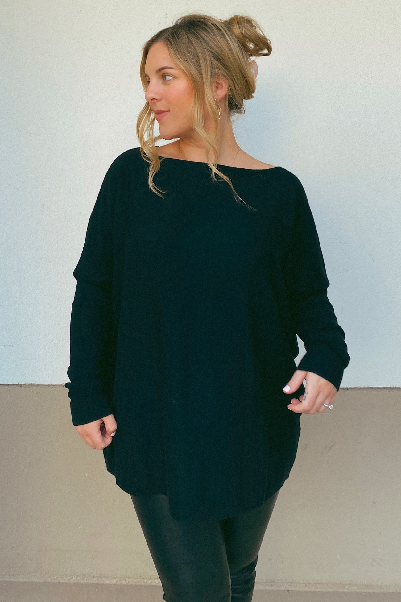 woman wearing a black oversized long sleeve top with a relaxed fit and stylish drape