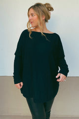 woman wearing a black oversized long sleeve top with a relaxed fit and stylish drape