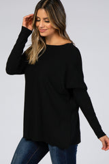 woman wearing a black oversized sweater with long sleeves and a scoop neckline paired with dark jeans