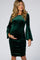 woman wearing a green velvet maternity dress with bell sleeves and ruching, holding her baby bump