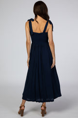 woman wearing a navy blue maxi dress with tie straps and a smocked bodice, shown from the back