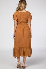 Back view of a woman wearing a rust orange smocked midi dress with flutter sleeves and tan block heels
