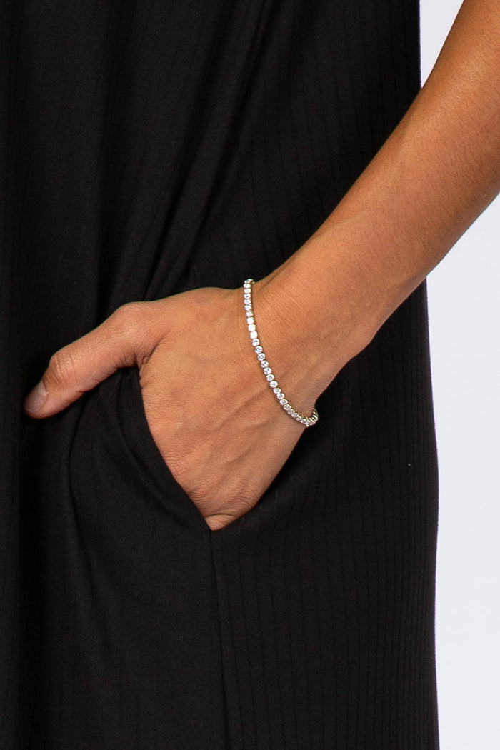 woman wearing a black ribbed dress with a silver bracelet on her wrist, hand in pocket