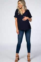 woman wearing a navy v-neck maternity top and blue skinny jeans, holding her baby bump