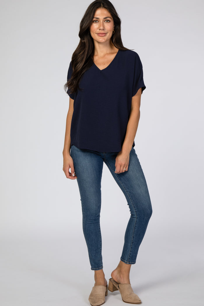 woman wearing a navy blue short sleeve v-neck top with jeans and beige mules