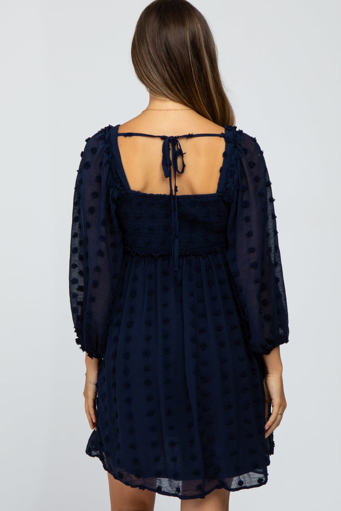 woman wearing a navy blue maternity dress with puff sleeves and a smocked back design