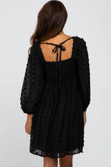 woman wearing a black polka dot dress with a smocked bodice and puff sleeves, tie detail at the back
